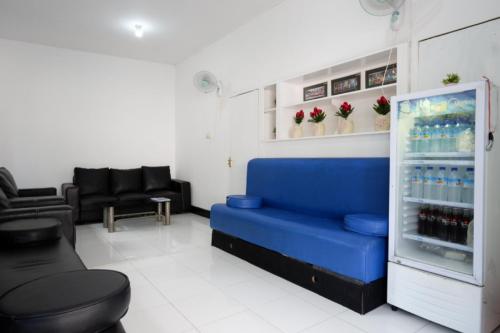 a room with a blue couch and a drink refrigerator at RedDoorz near Mataram University in Mataram