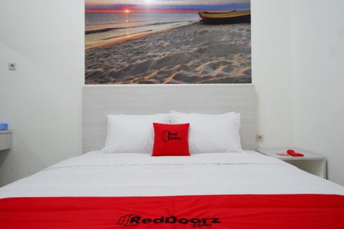 a red pillow sitting on top of a bed at RedDoorz near Mataram University in Mataram