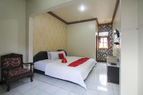 a bedroom with a white bed and a chair at RedDoorz near Sarangan Lake in Magetan