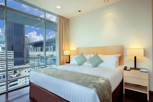 a bedroom with a large bed and a large window at PARKROYAL Serviced Suites Kuala Lumpur in Kuala Lumpur