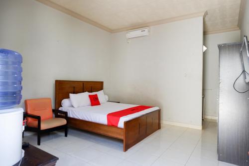um quarto com uma cama e uma cadeira em RedDoorz near Mutiara SIS Al Jufrie Airport Palu em Palu