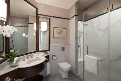 a bathroom with a sink and a toilet and a shower at Raffles Grand Hotel d'Angkor in Siem Reap