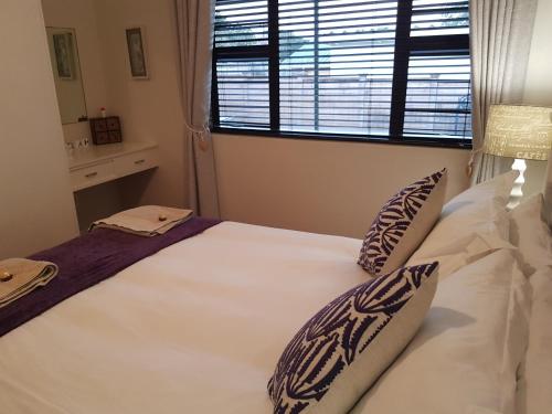 a bedroom with a large white bed with pillows and a window at Bushys Oak in Bushmans River Village