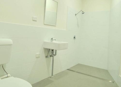 a white bathroom with a toilet and a sink at Argyle Hotel Southern Highlands in Moss Vale