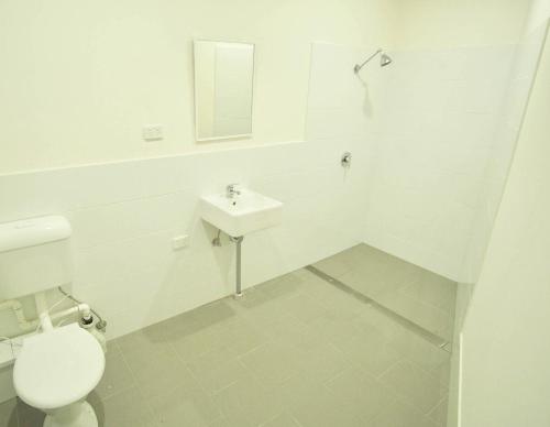 a white bathroom with a toilet and a sink at Argyle Hotel Southern Highlands in Moss Vale