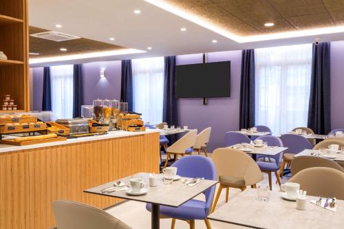a dining room with tables and chairs and a screen at Best Western Le Beffroi in Loos