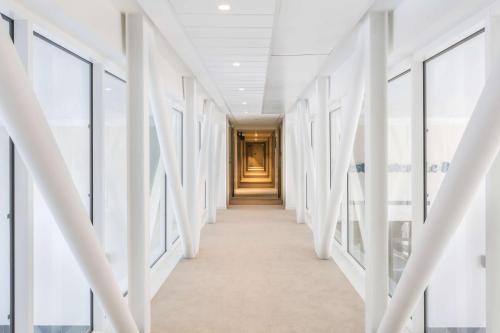 a hallway in a building with white walls and windows at Best Western Le Beffroi in Loos