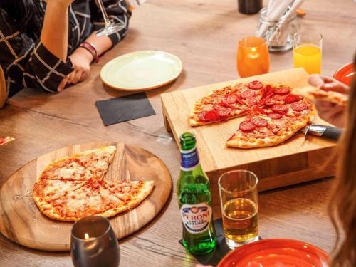 two slices of pizza on a wooden table with drinks at ibis Styles London Gloucester Road in London
