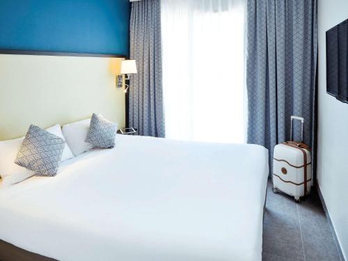 a hotel room with a white bed and a suitcase at Aparthotel Adagio Monaco Monte Cristo in Beausoleil