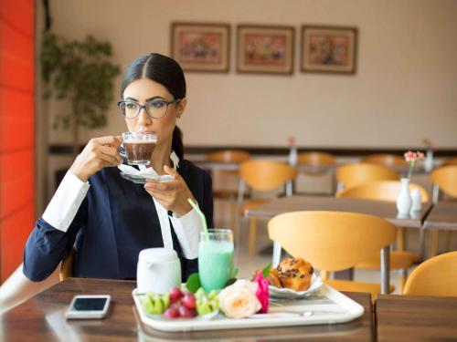 a woman sitting at a table with a plate of food at Ibis Marrakech Palmeraie in Marrakech