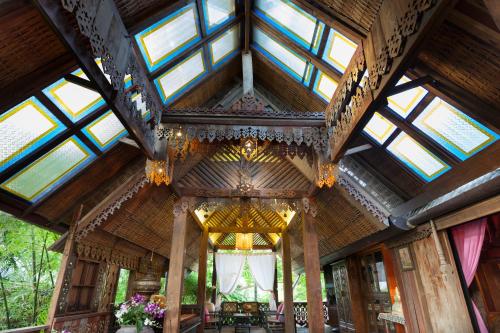 a large wooden building with a roof with windows at BaanBooLoo Village in Chiang Mai