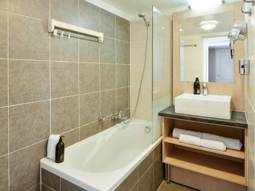 a bathroom with a tub and a sink at Aparthotel Adagio Monaco Monte Cristo in Beausoleil