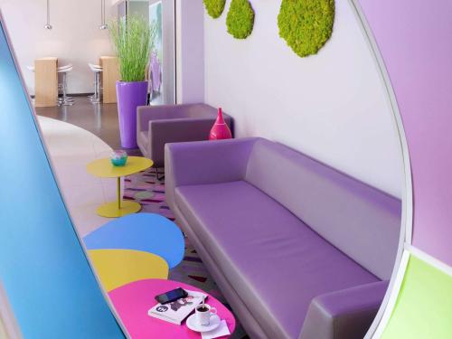 a room with a purple couch and a mirror at ibis Styles Montbéliard in Montbéliard