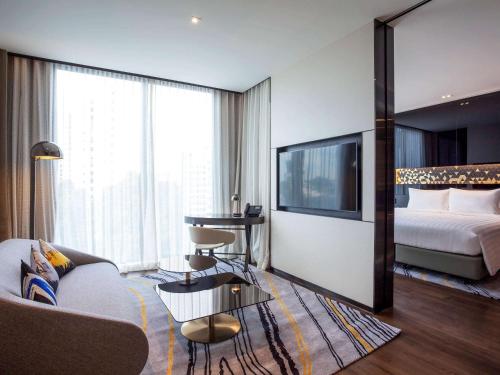 a hotel room with a couch and a bed and a tv at Novotel Singapore On Stevens in Singapore
