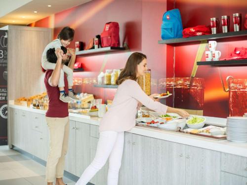two women and a child are preparing food at a counter at Ibis Casa Voyageurs in Casablanca