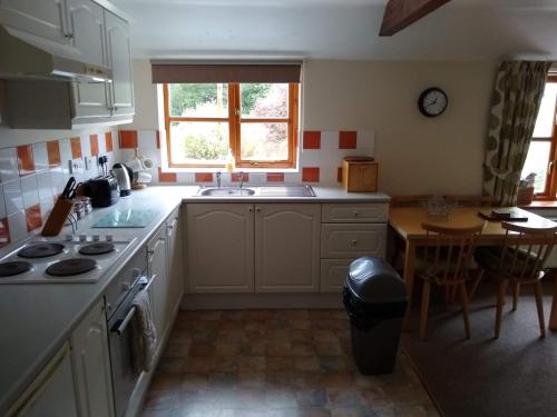 a kitchen with a stove and a sink and a table at Swallow cottage in Louth