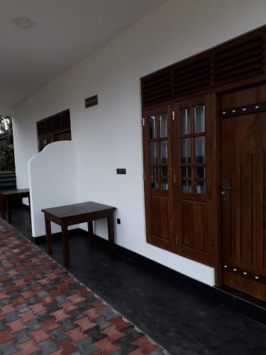 a room with a table and a wooden door at The Wave's Guest House in Mirissa