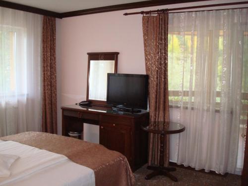 a bedroom with a bed and a television and a window at Pensiunea Carmen Silvae in Gura Humorului