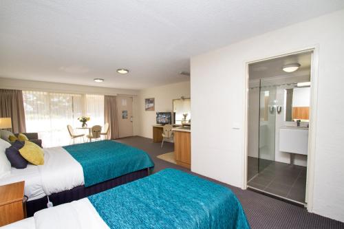 a hotel room with two beds and a television at Fairway Motor Inn in Merimbula
