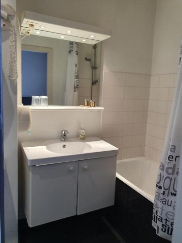 a bathroom with a sink and a mirror and a tub at Hotel Queen Mary in Brussels