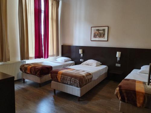 2 camas en una habitación de hotel con cortinas rojas en Hotel Queen Mary, en Bruselas