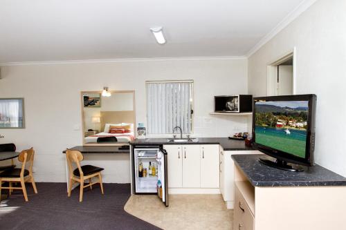 a kitchen with a refrigerator and a tv in a room at Fairway Motor Inn in Merimbula