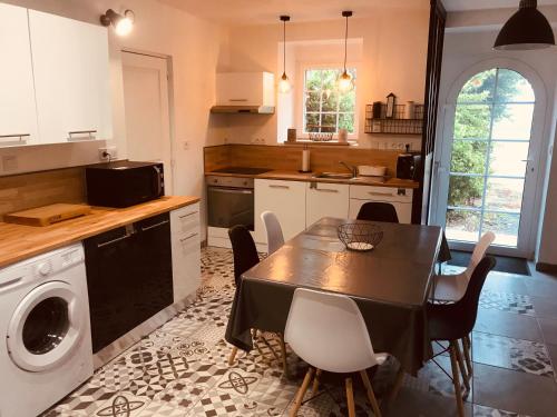 eine Küche mit einem Tisch und eine Küche mit einem Geschirrspüler in der Unterkunft Maison en pierre entièrement rénovée. in Trébry