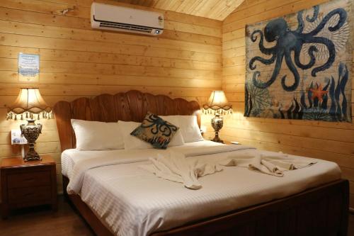 a bedroom with a bed with white sheets and an octopus painting at Montego Bay Beach Village - Morjim in Morjim