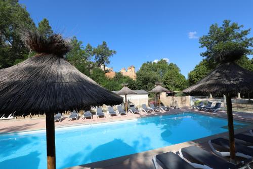 uma piscina com guarda-sóis e cadeiras em Camping le Colorado em Rustrel