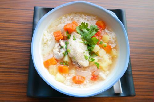 a bowl of soup with chicken and carrots on a table at Baan i Talay Chumphon บ้านไอทะเลชุมพร in Chumphon