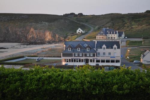 a large white house on a hill with a beach at Hôtel de la Baie des Trépassés in Plogoff