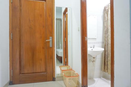 bagno con porta in legno e lavandino di Residences by RedDoorz Syariah @ Buah Batu a Bandung
