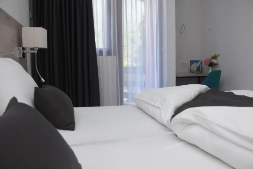 a bedroom with two white beds and a window at Hotel Mladost in Tjentište