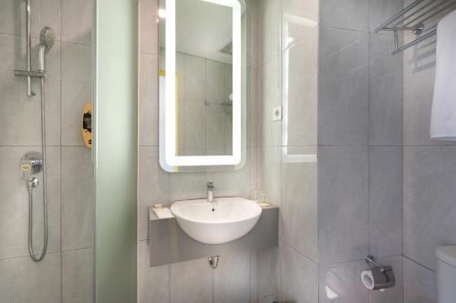 uma casa de banho com um lavatório, um espelho e um chuveiro em Yello Hotel Manggarai em Jakarta