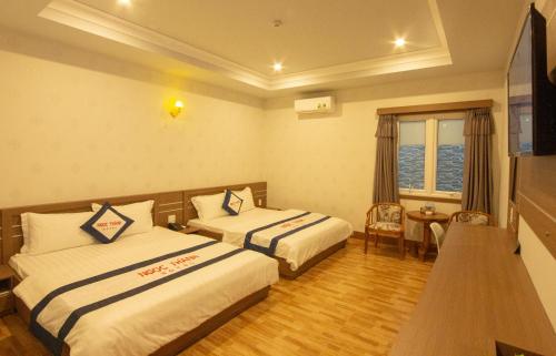 a hotel room with two beds and a table at Khách sạn Ngọc Thành 2 in Rach Gia