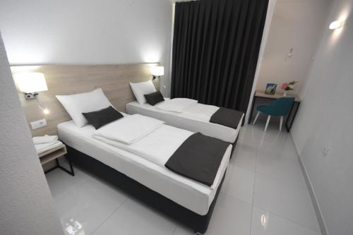 a hotel room with two beds and a desk at Hotel Mladost in Tjentište