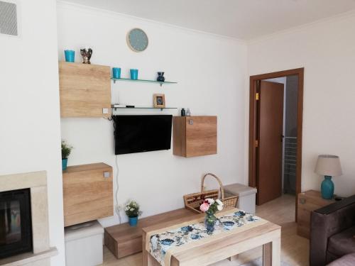 uma sala de estar com uma mesa e uma televisão em Grand Monastery - Azure Apartment em Pamporovo