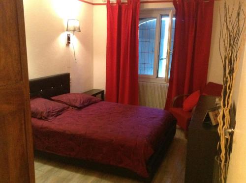 una camera con letto e finestra con tende rosse di Gîte la Genestière a Sérignan-du-Comtat