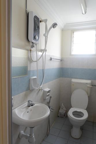 a bathroom with a sink and a toilet and a tv at Permai Seri Homestay in Ampang