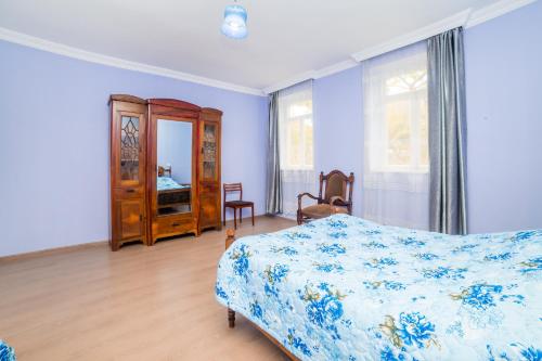 a bedroom with a bed and a dresser and windows at Nukri Guest House in Gori