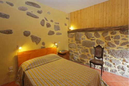um quarto com uma cama e uma parede de pedra em Quinta do Galgo em Amares