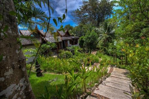 a house in the middle of a garden at Luxury 4 bedrooms Villa with Seaview Infinity Pool overlooking Surin Beach in Surin Beach