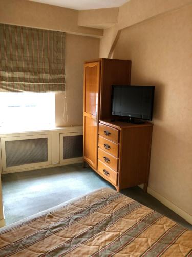 a bedroom with a flat screen tv and a dresser with a flat screen television at LE CABOUILLET in LʼIsle-Adam