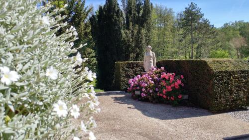 a statue in a garden next to some flowers at La Closerie in Droue-sur-Drouette