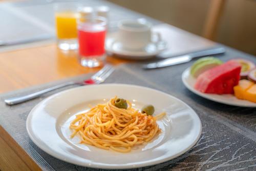 une assiette de spaghettis et de fruits sur une table dans l'établissement Greenery Hotel, à Đà Nẵng