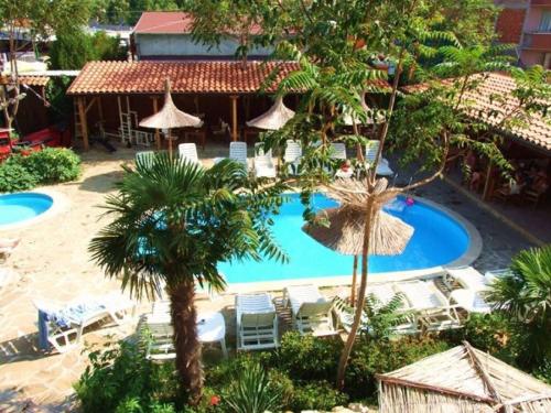 un complejo con piscina, sillas y palmeras en Family hotel Tropicana, en Ravda