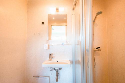 a bathroom with a sink and a shower with a mirror at Hotel Vagar in Sørvágur