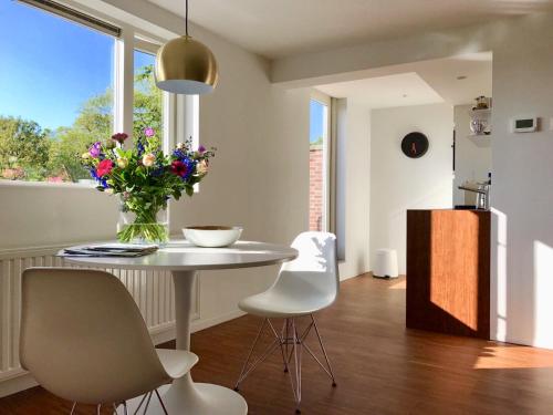 een keuken met een tafel en stoelen en een vaas met bloemen bij Slapen op 11 in Bergen op Zoom