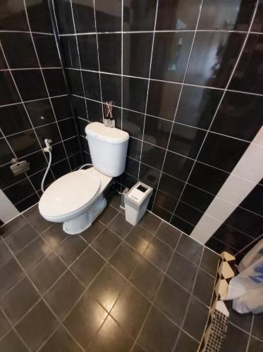 a bathroom with a toilet in a black tiled room at NB House in Karon Beach