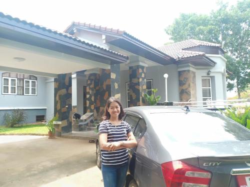 a woman standing next to a car in front of a house at บ้านนกเคียงจัน ปากช่อง Nok Kiang Chan Home Pak Chong in Ban Nong Ka Cha